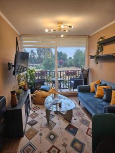 a living room with a blue couch and a table at Departamento en condominio a 10min del centro in Puerto Montt