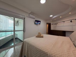 a bedroom with a bed and a large window at RG01- 3 Suítes| Pé na Areia| Vista Mar| Churrasq in Balneário Camboriú