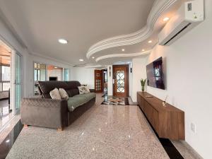 a living room with a couch and a tv at RG01- 3 Suítes| Pé na Areia| Vista Mar| Churrasq in Balneário Camboriú