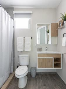 a white bathroom with a toilet and a sink at AQUA Terrazas Studio 7 - Beachfront Getaway with King Bed & Pool in Dorado
