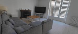 a living room with a couch and a tv and a table at logement familial spacieux, 2 chambres , grand salon in Fougères