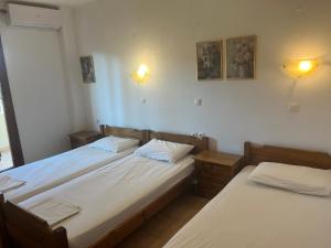 two twin beds in a room with two lights at Hotel Kosmas in Sarti