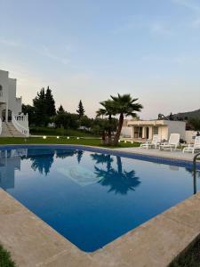a large blue swimming pool with chairs and a house at Bungalow amsa in Amsal