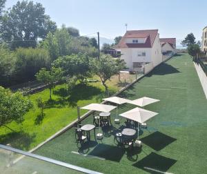 a group of tables with white umbrellas on a lawn at Pes Na Area Fisterra 02 in Fisterra
