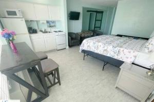 a bedroom with a bed and a table and a kitchen at Stylish Studio Ocean View in Daytona Beach