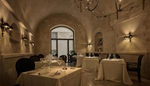 a restaurant with white tables and chairs and a window at Palazzo Gattini - The Leading Hotels of the World in Matera