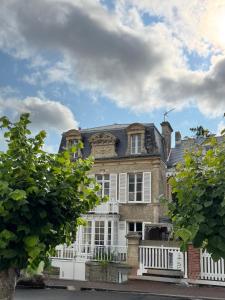 a large brick house with a white fence at La Villa Graziella in Arromanches-les-Bains