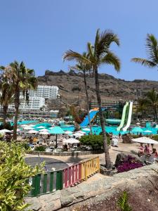 a beach with palm trees and a water park at Taurito Bay in Taurito