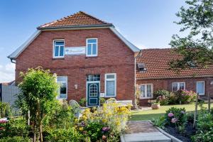 朗格奥ELSE in der 'Stranddistel'的一栋有蓝色窗户和院子的红砖房子