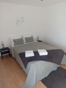 a bedroom with a large bed with two towels on it at A Casa da Carmita in Pedrógão Grande
