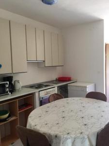 une cuisine avec une table et des chaises et une cuisine avec des placards blancs dans l'établissement Appartements Prisika Novi, à Novi Vinodolski 14 autres photos