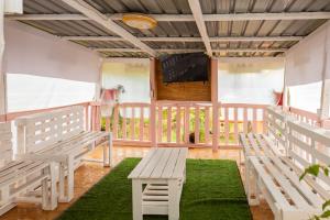 een veranda met twee banken en een televisie bij Elmadel Coffee Gardens 4Bed Rustic Wooden House in Machakos