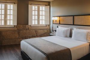 a hotel room with a large bed with white pillows at Timbre Virtudes in Porto