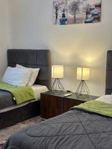 een slaapkamer met 2 bedden en 2 lampen op een tafel bij prime homes in Banī Ghālib