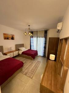 een slaapkamer met 2 bedden met rode lakens en een raam bij prime homes in Banī Ghālib