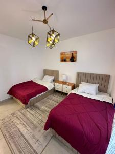 een slaapkamer met 2 bedden en een kroonluchter bij prime homes in Banī Ghālib