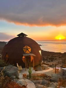 Una casa abovedada con una puesta de sol al fondo en DomoChango, en La Serena