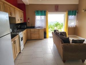 a kitchen with a couch and a kitchen with a window at Nia's Hillside Apartment - Amazing Scenery in Grande Rivière