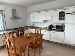 a kitchen with a wooden table and white cabinets at CASA Nieves in O Grove