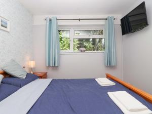 a bedroom with a bed with blue curtains and a tv at Boos Bungalow in Callington +36 photos