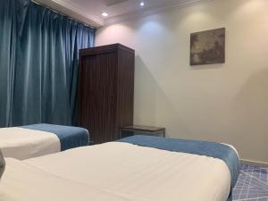 a hotel room with two beds and a cabinet at القصر الضيافة 2 in Khamis Mushayt