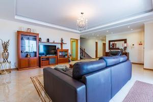 un soggiorno con un grande divano e una TV di Great villa with covered swimming pool and sea view in Calheta Hasta La Vista ad Arco da Calheta