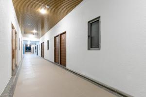 a hallway with white walls and wooden doors at Hotel O C3 Celebration City Centre in Bodakdev