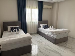 a bedroom with two beds and a window with blue curtains at Zayed hotel in Sheikh Zayed