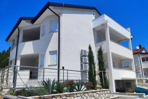 a large white house with plants in front of it at Sky apartment, Island Rab in Rab