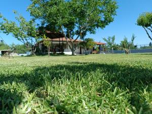 a field of grass with a house in the background at Kanela House ,Cozy Cottage with Large Garden & BBQ in Nea Kallikrateia