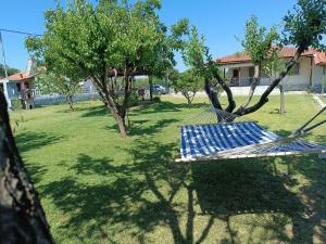 a hammock in a yard with trees and a building at Kanela House ,Cozy Cottage with Large Garden & BBQ in Nea Kallikrateia