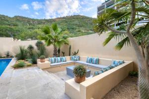 a living room with a couch and palm trees at New 3 BD Condo with Pool and Gym in Cabo San Lucas