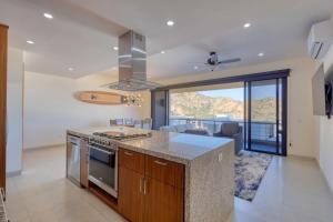 a kitchen with a stove top oven next to a living room at New 3 BD Condo with Pool and Gym in Cabo San Lucas