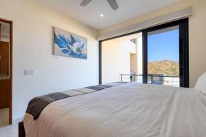 a bedroom with a large bed with a large window at New 3 BD Condo with Pool and Gym in Cabo San Lucas +27 photos