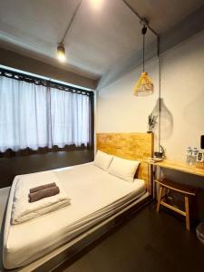 een slaapkamer met een bed, een bureau en een raam bij EK Silomhostel in Bangkok +7 foto's