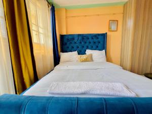 un grande letto con testiera blu in una stanza di Studios in roysambu a Nairobi