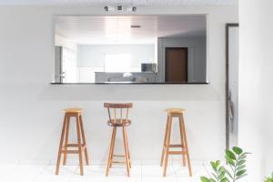 a kitchen with three wooden stools and a mirror at Pousada Gonçalves in Tangará
