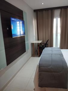 a bedroom with a bed and a flat screen tv at Apartamento Flat Itaboraí - Edifício Hélix in Itaboraí