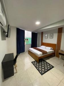 una camera da letto con un letto, una scrivania e una televisione di Suites Avenida a Machala