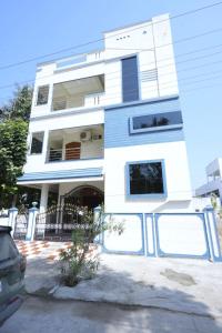 Una casa blanca con un coche aparcado delante. en Newly Built Beautiful and Luxurious 3BHK in Tirupati with Fully Functional Kitchen,for upto 25 guests, en Tirupati