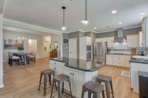 a large kitchen with white cabinets and bar stools at Woodlands Grand 3BR Cozy House in The Woodlands