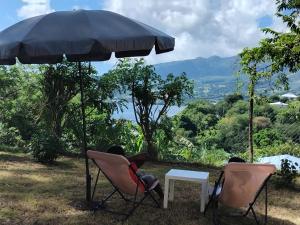 two people sitting in chairs under an umbrella at Carbet Horizon in Le Carbet