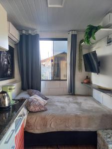 a small room with a large bed in a kitchen at Tiny House Aconchego in Canoinhas