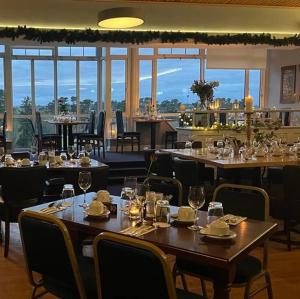 a dining room with tables and chairs and windows at Tramore Golf Club Lodge Room - Bar & Bistro Onsite in Tramore