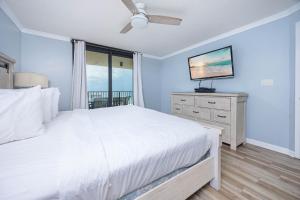 a bedroom with a white bed and a flat screen tv at Phoenix IV 4053 condo in Orange Beach +50 photos