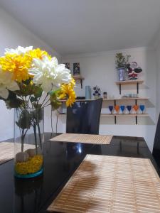 a vase with yellow and white flowers on a table at Hotel Parkway Inn 58 Street in Bogotá