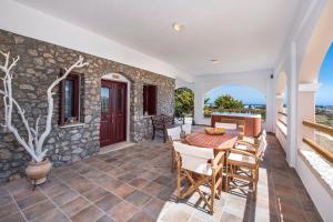 a patio with a table and chairs and a stone wall at Summer House Collection - A Secluded Getaway in Perissa