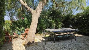 una mesa y sillas sentadas junto a un árbol en Pool Sea & Country side Villa, en Aldeia de São Pedro