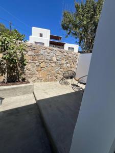 a patio with two chairs and a stone wall at Oro suites budget in Mikonos