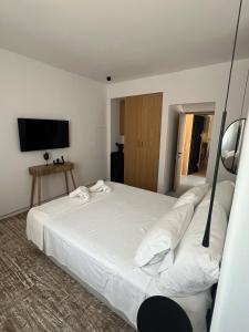a bedroom with a large white bed with a flat screen tv at Oro suites budget in Mikonos